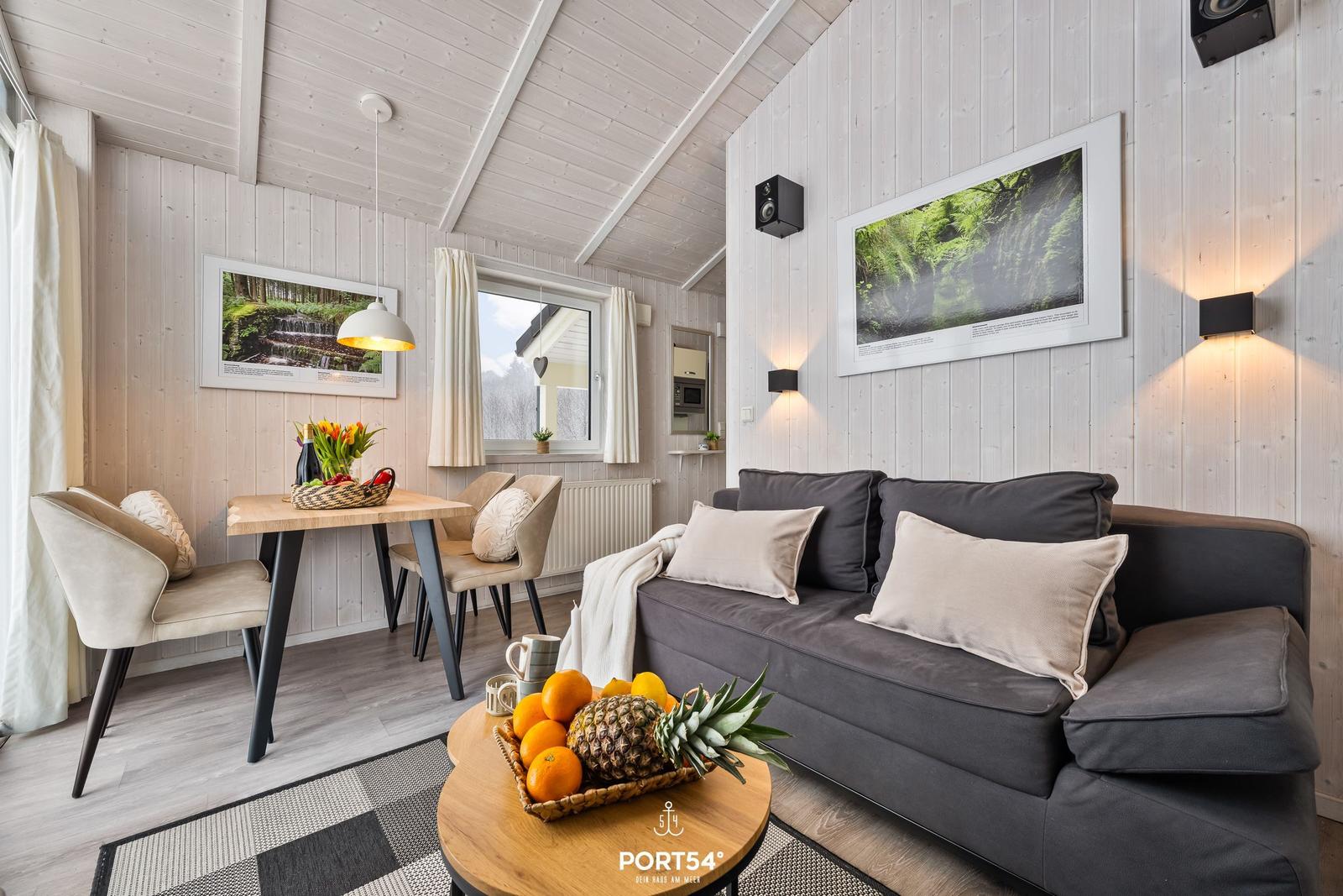 Wohn- und Essbereich mit Sofa, Tisch und Wandbildern.
