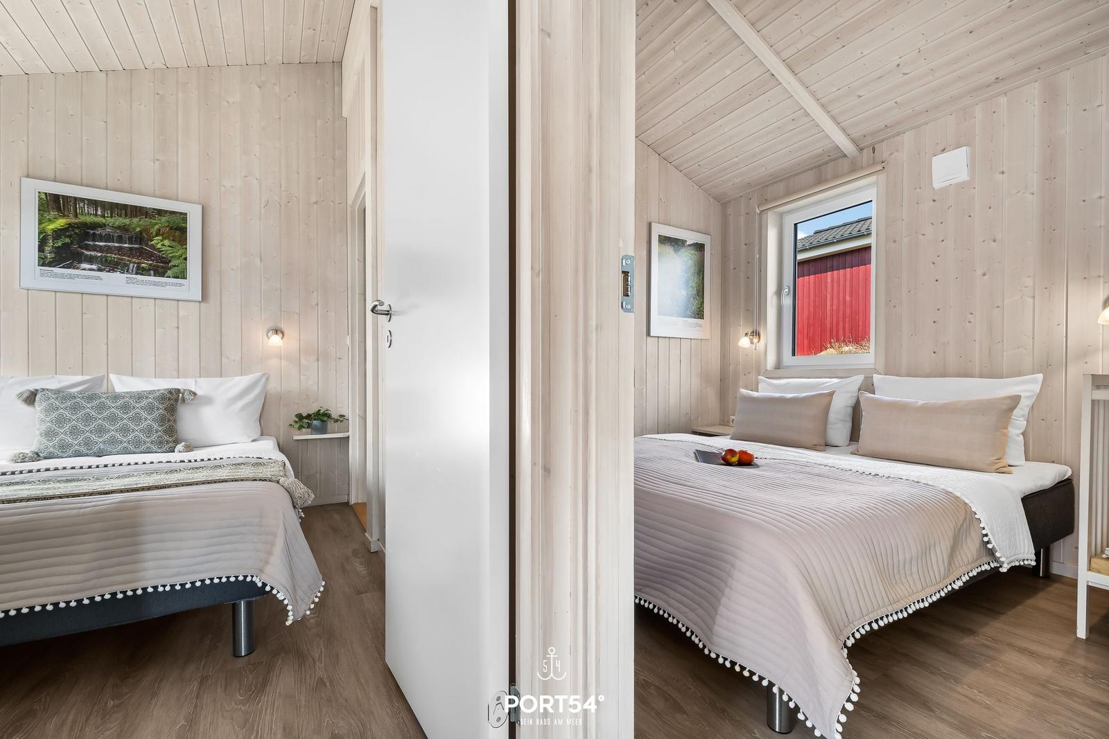 Zwei Schlafzimmer mit Holzwandverkleidung und Betten. Ein Fenster zeigt einen roten Anbau.