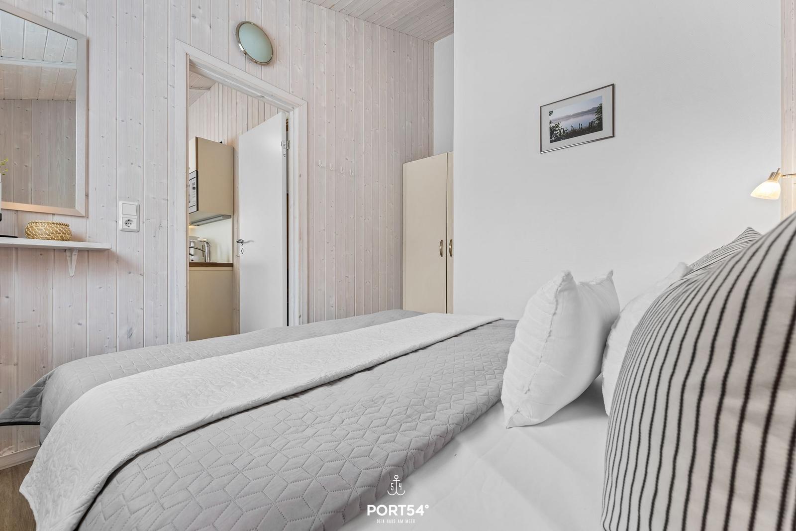 Schlafzimmer mit Bett, Kleiderschrank und Blick in die Küche.