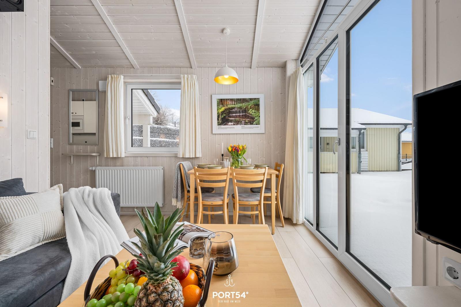 Living and dining area with wooden walls, table, chairs, and view of the outdoor area.