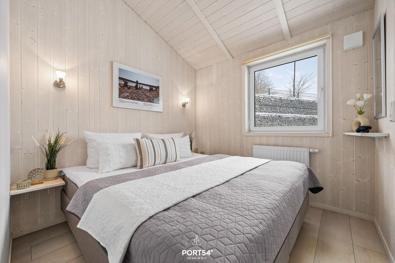 Bedroom with bed, window, and wood paneling.