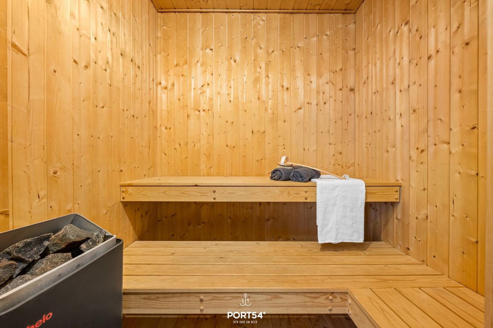 Sauna with wooden walls, bench, and stones in the stove.