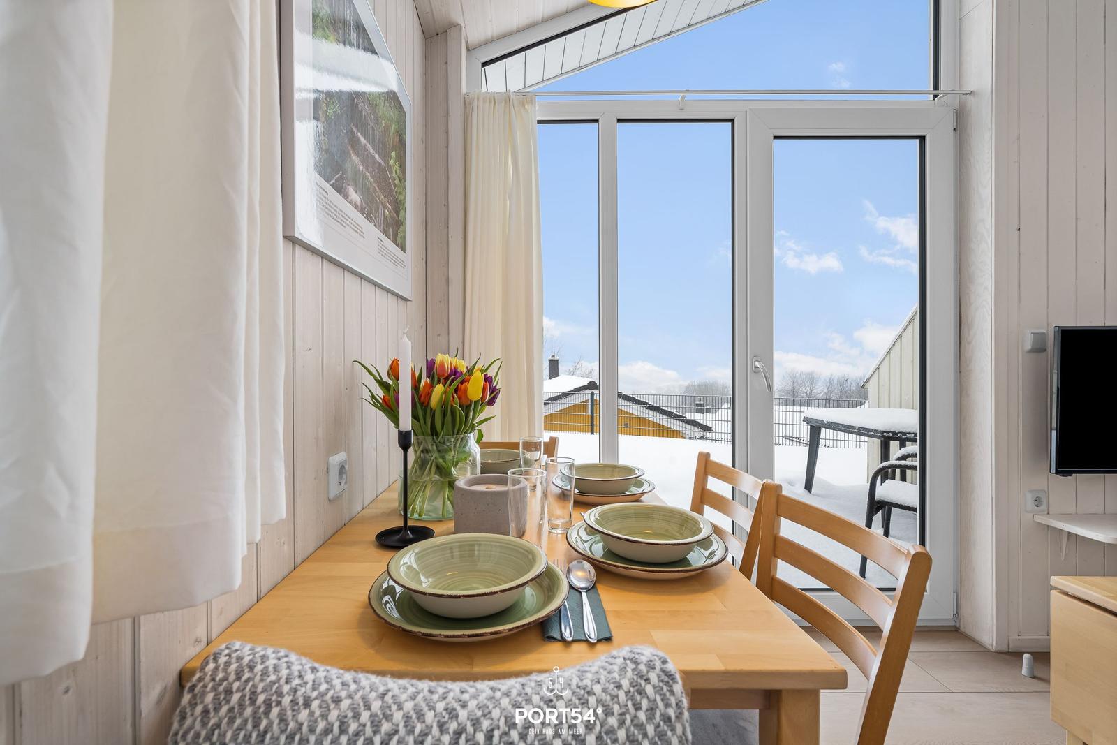 Dining room with table, chairs, and view of snowy balcony.