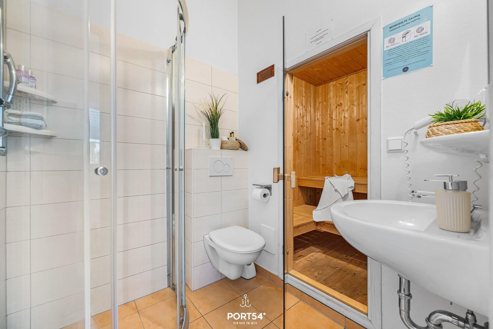 Bathroom with shower, toilet, and sauna. Wooden sauna with benches.