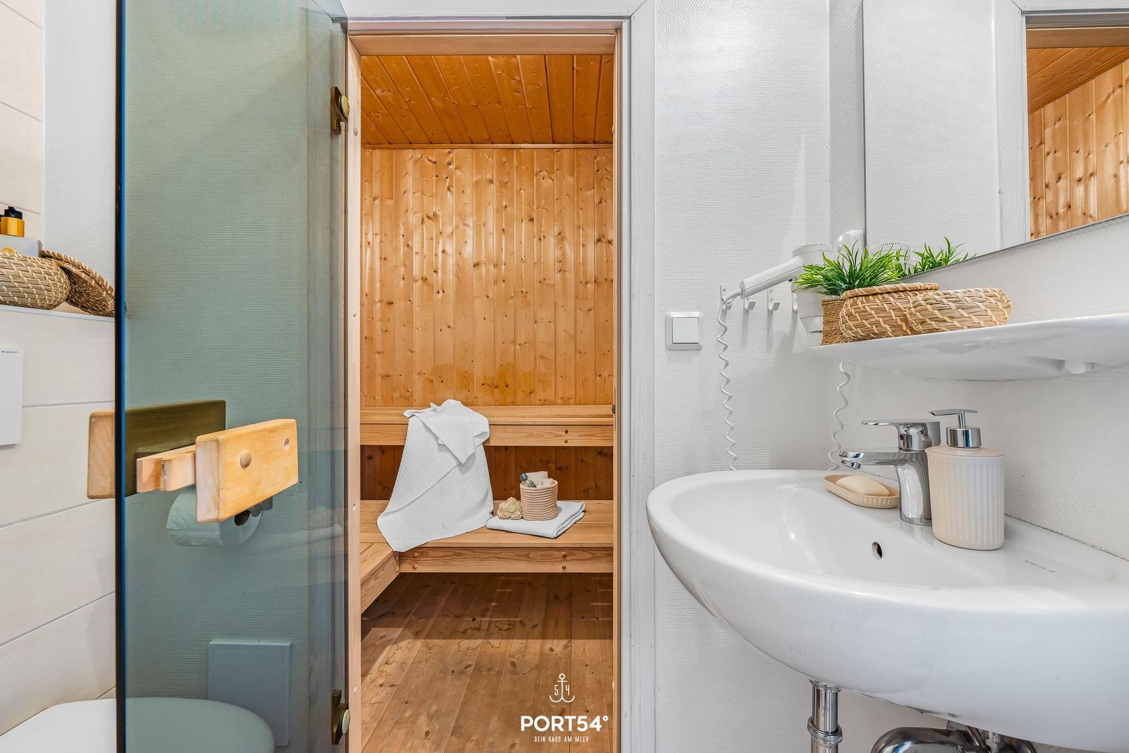 Bathroom with shower, sink, and sauna with wooden cladding.