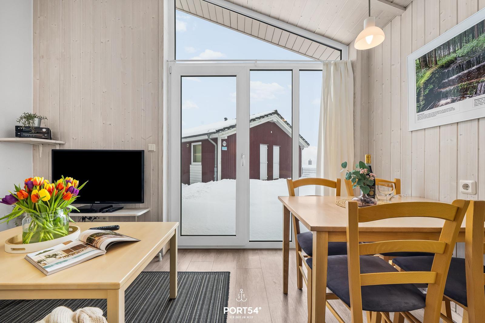 Living and dining area with wooden furniture and view of snowy landscape.
