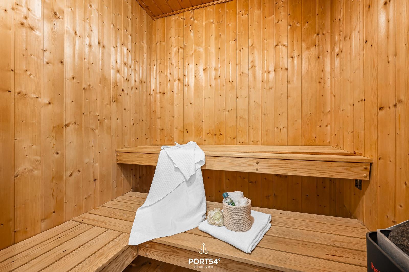 Sauna with wooden walls, bench, and towels