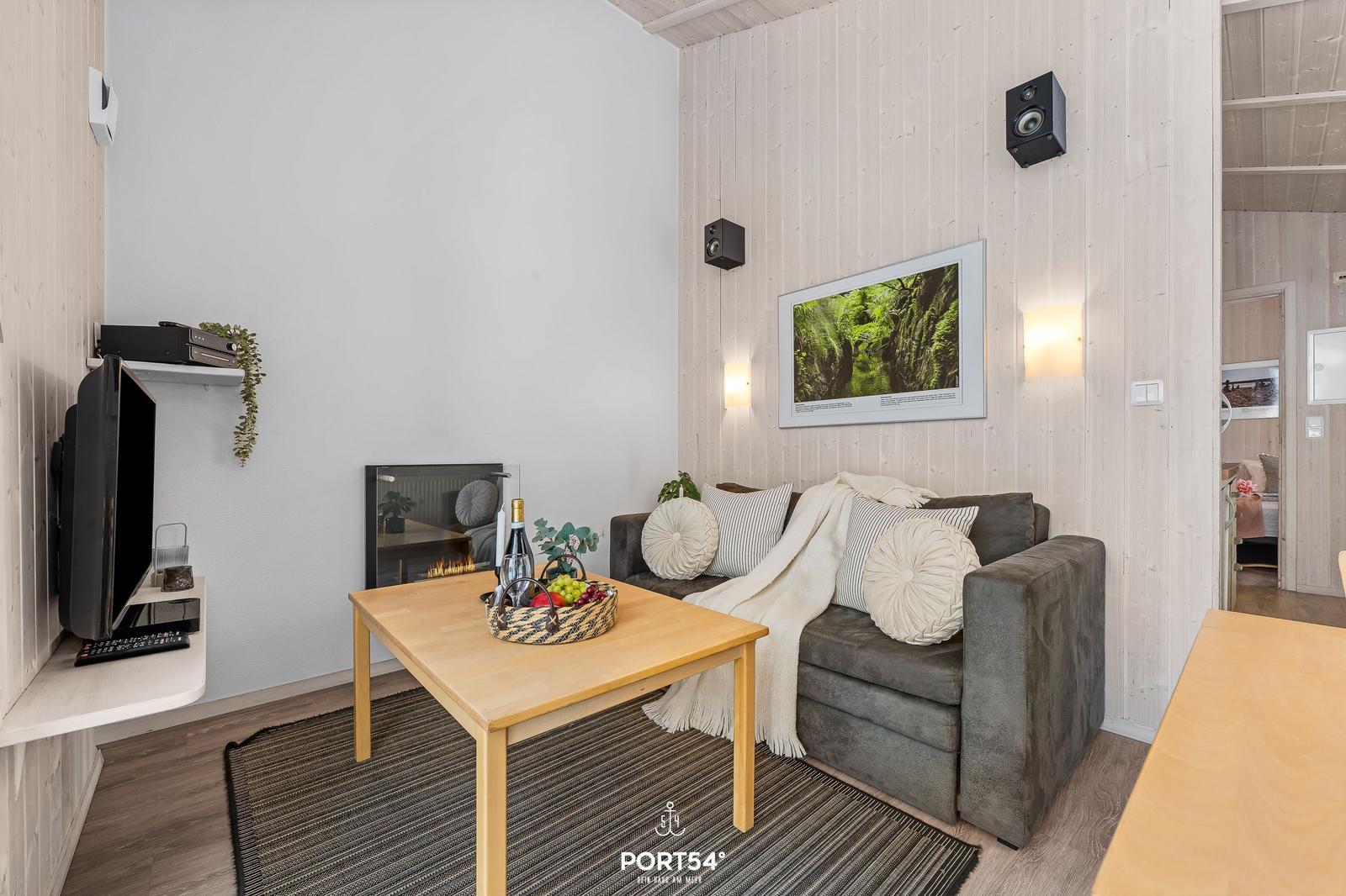 Wohnzimmer mit Sofa, Couchtisch und Kamin. Wandbild und Lautsprecher an der Wand.