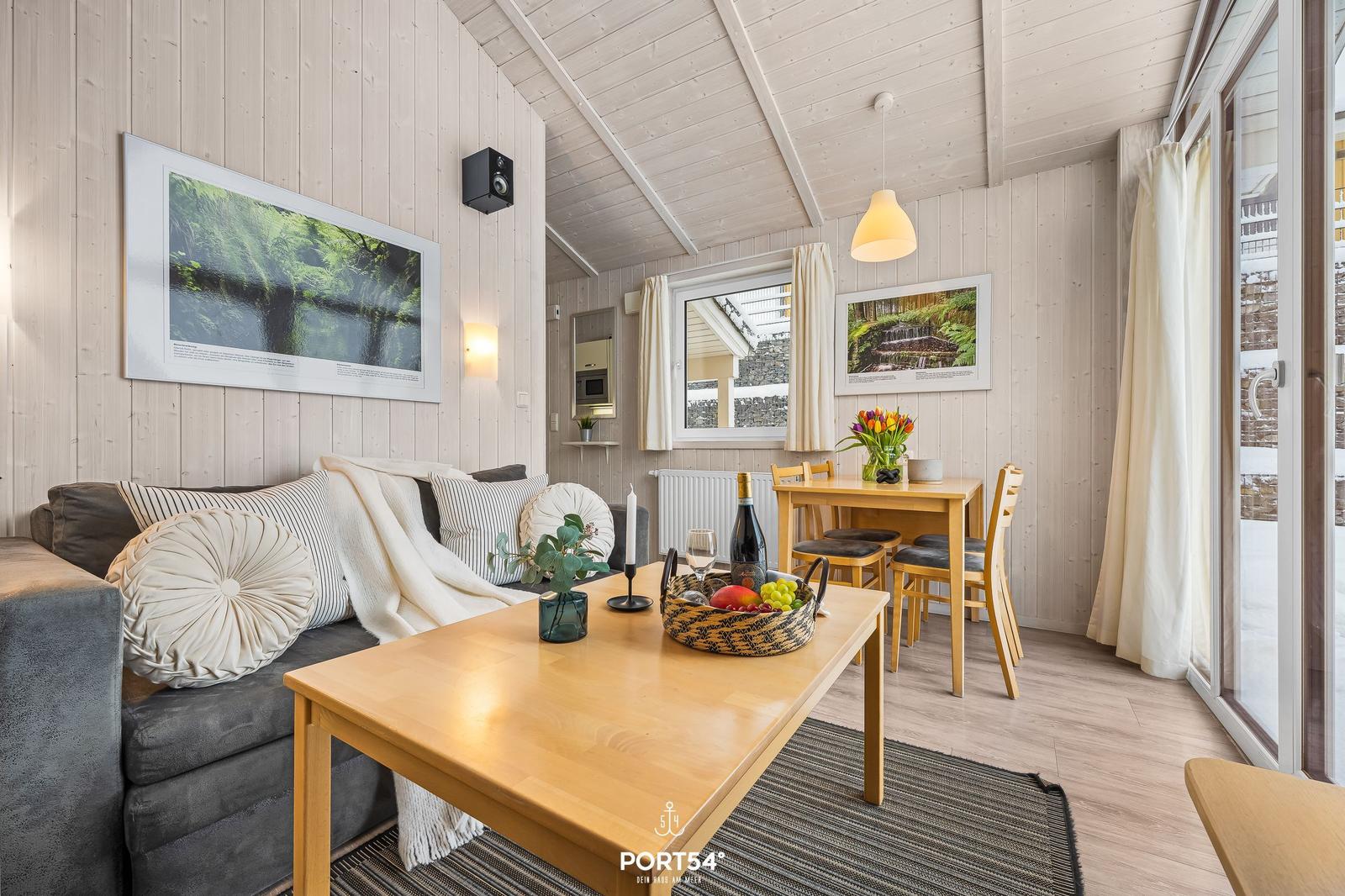 Wohn- und Essbereich mit Holzmöbeln, Sofa, Tisch und Fenster.