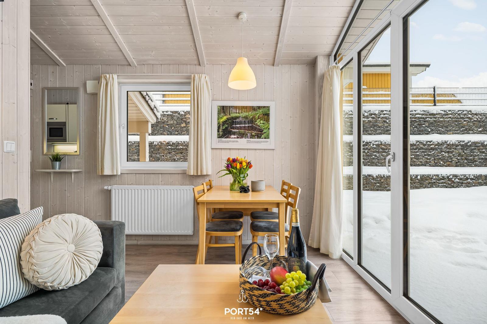 Wohnraum mit Essbereich, Schnee draußen und Holzwandverkleidung.