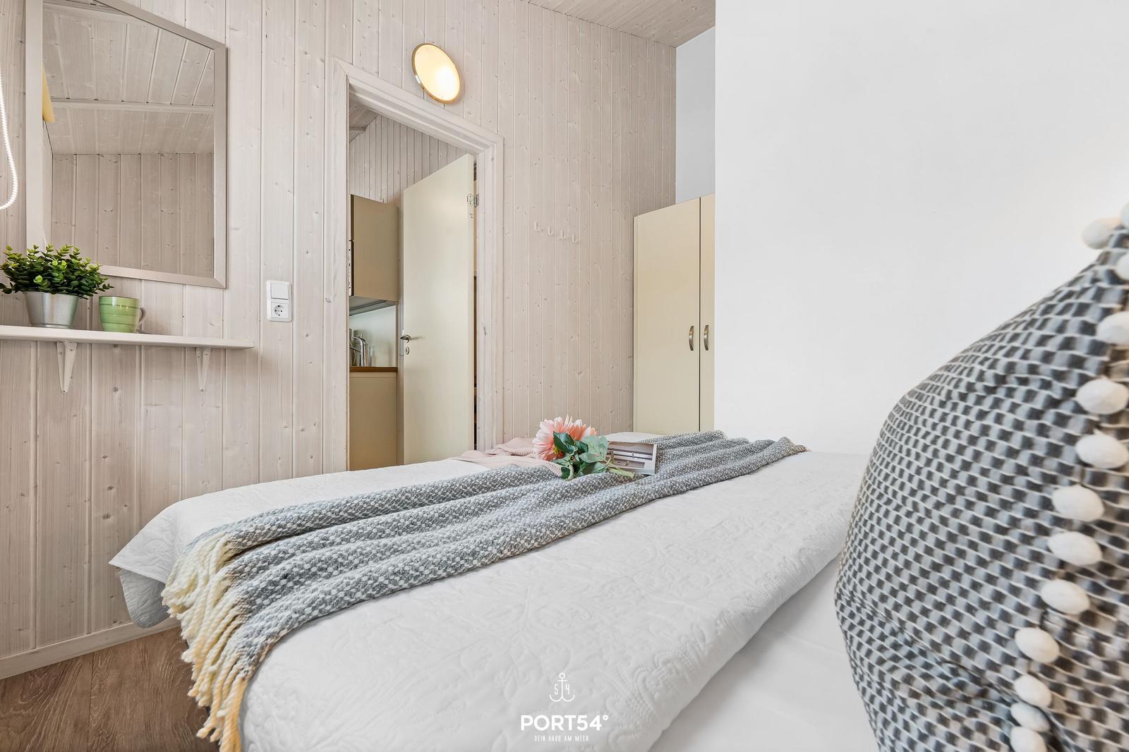 Schlafzimmer mit Bett, Kleiderständer und Spiegel an der Wand