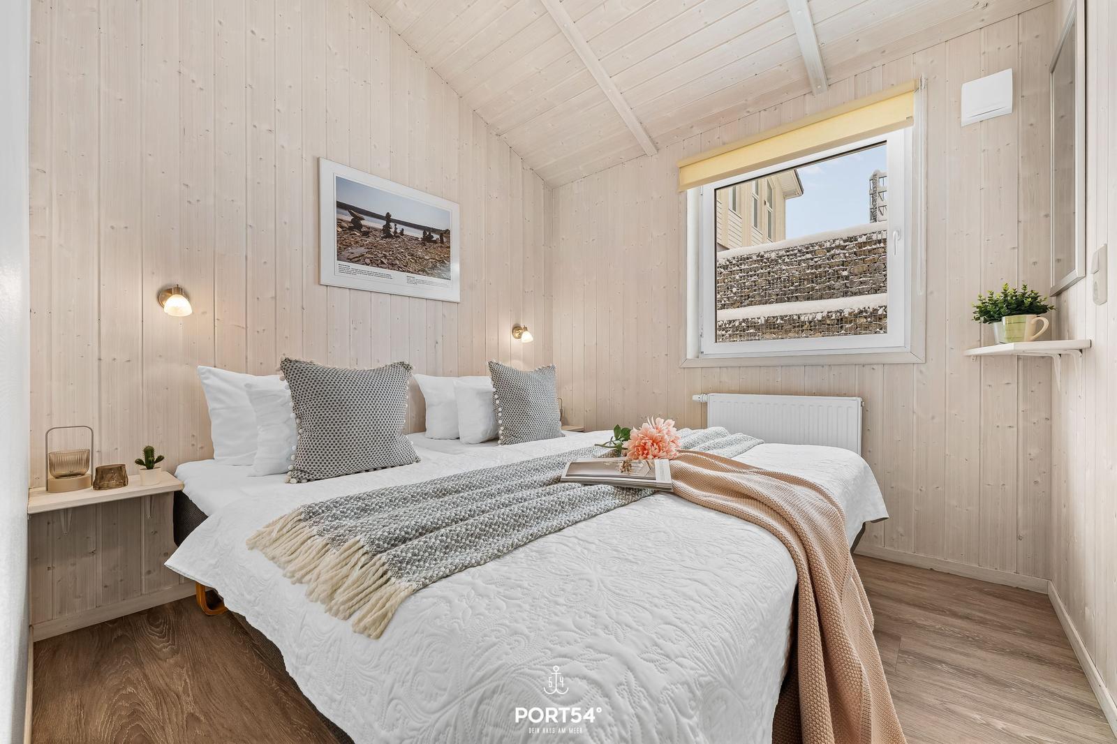 Schlafzimmer mit Holzwand, Bett, Fenster und dekorativen Elementen.