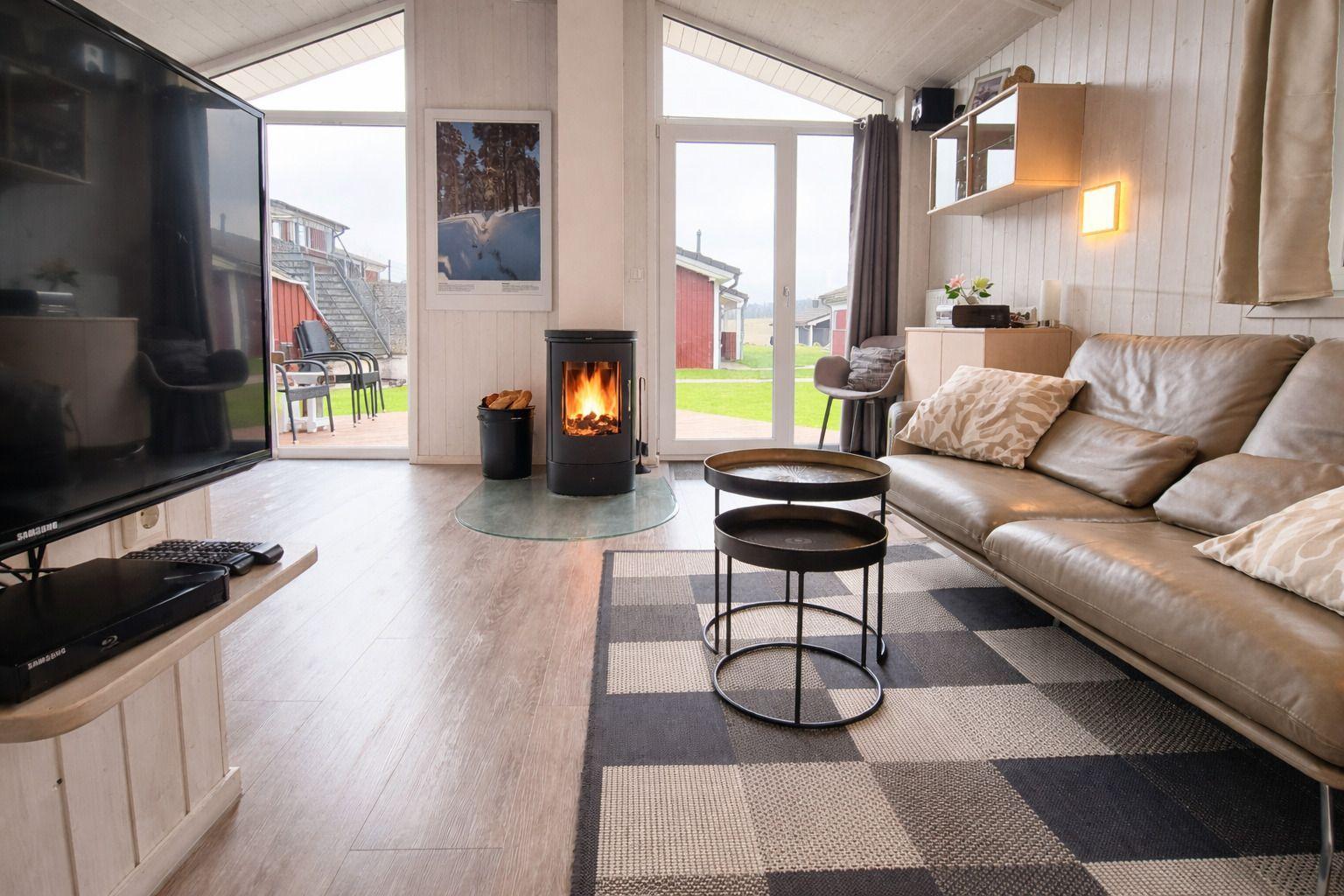 Wohnzimmer mit Kamin, Sofa und TV. Durchgänge zu einer Terrasse und Garten.