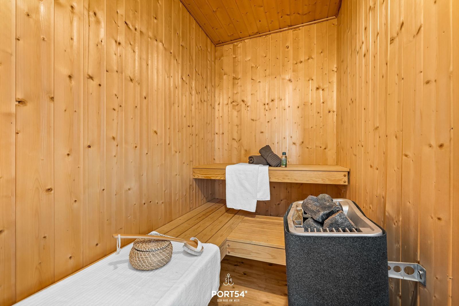 Sauna mit Holzwand, Liegefläche, Handtuch und Steine