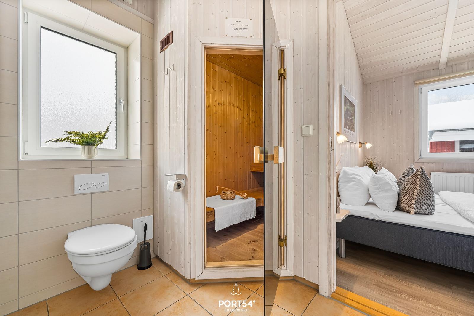 Bad mit Toilette, Sauna und Schlafzimmer mit Bett und Fenster.