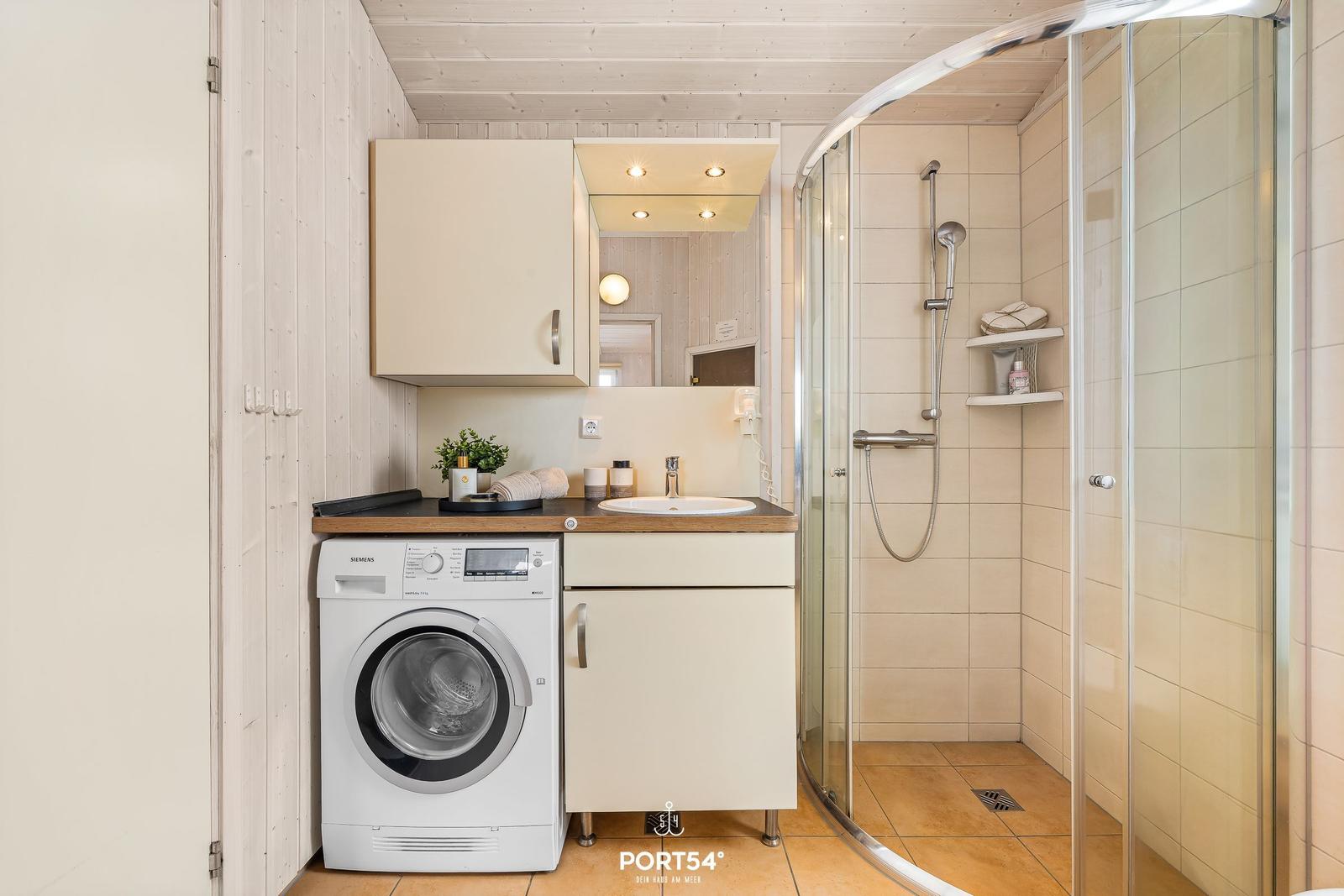 Badezimmer mit Dusche, Waschmaschine und Spiegel
