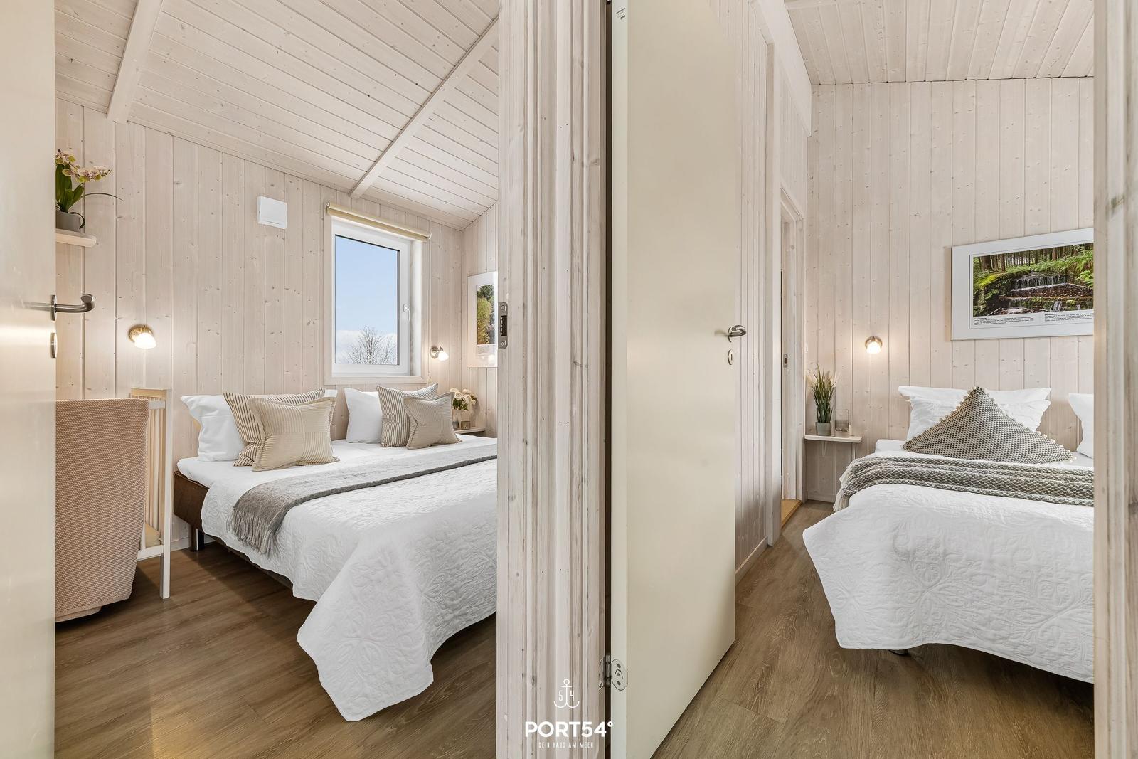Zwei Schlafzimmer mit Holzwänden und Betten mit weißen Bettwäschen.
