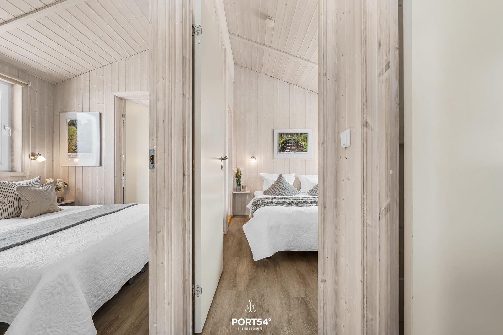Zwei Schlafzimmer mit Holzwänden und Betten. Ein Raum hat ein Fenster, der andere eine Tür.