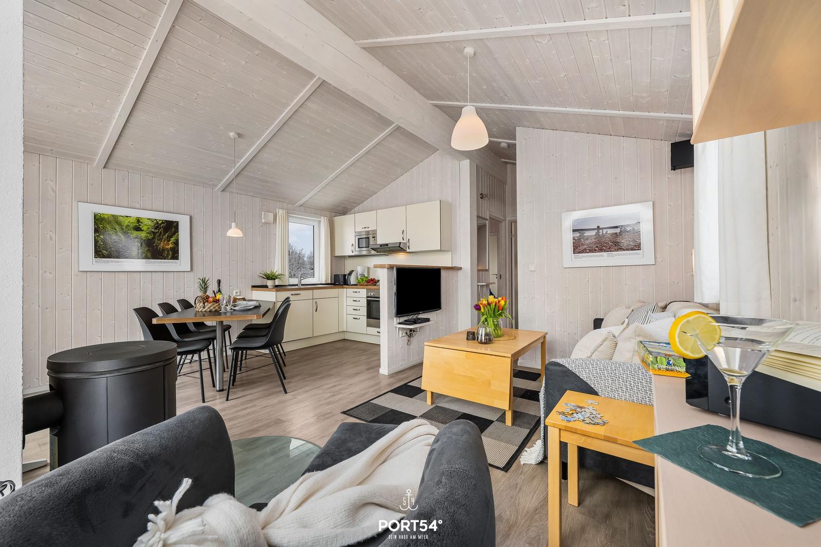 Wohnbereich mit Essbereich, Küche und Sofa. Holzdecke, Bilder an den Wänden.