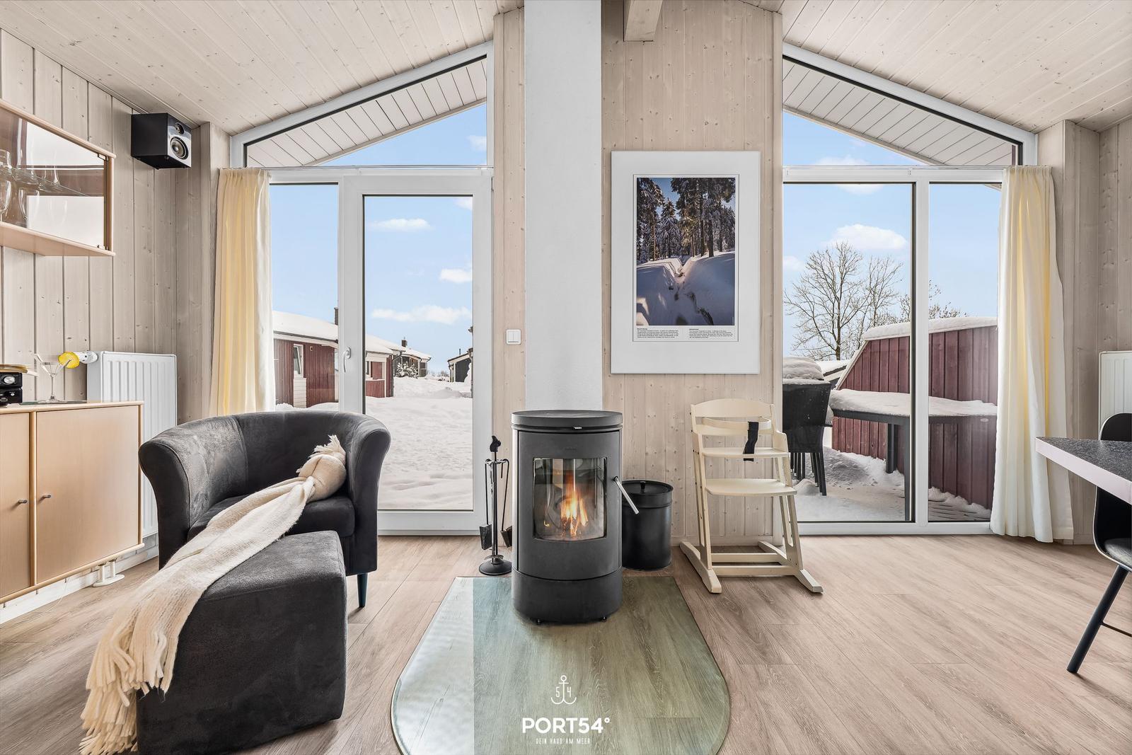 Wohnzimmer mit Kamin, Sofa und Blick auf Schnee.