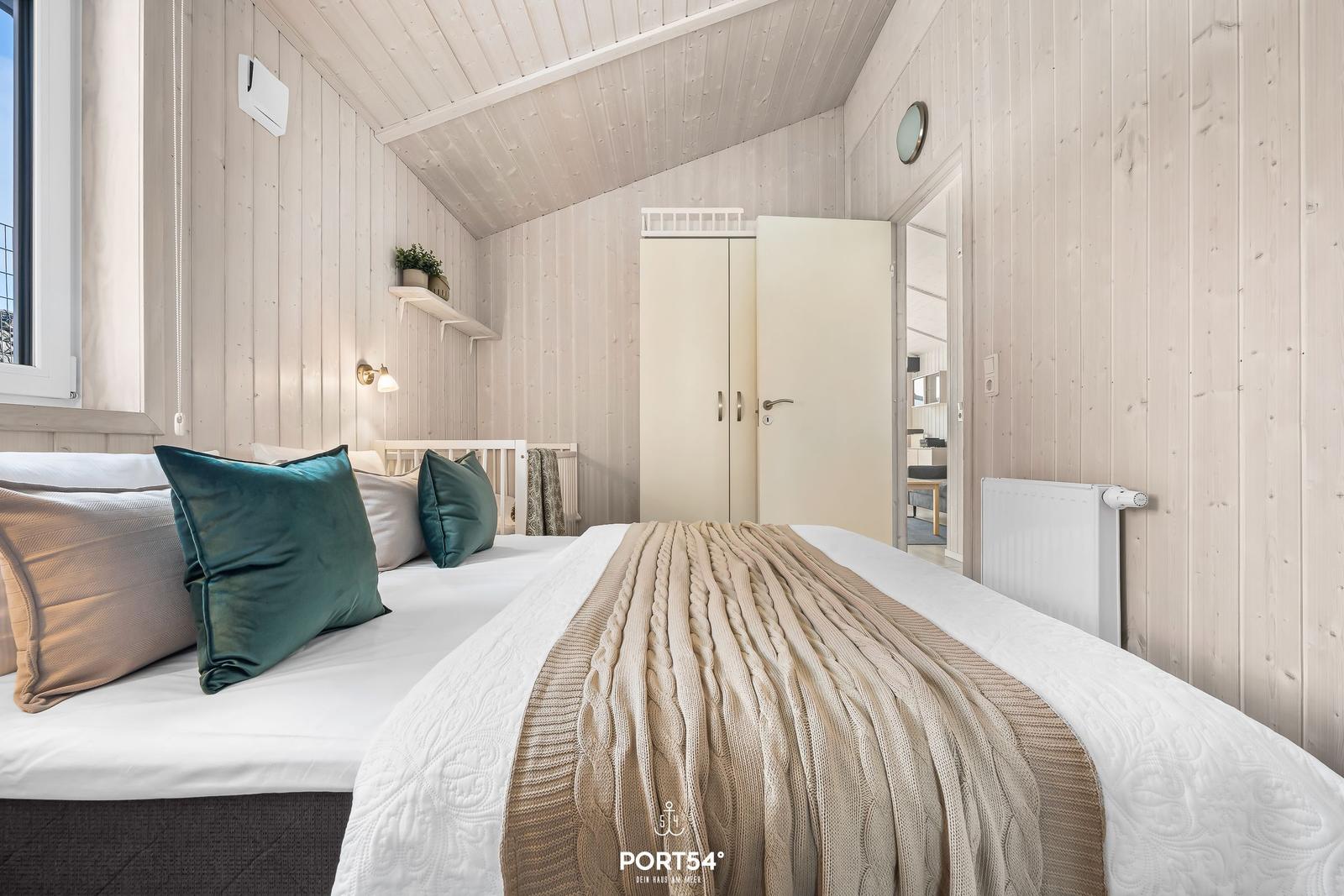 Schlafzimmer mit Bett, Kleiderschrank und Fenster. Holzwand und Decke.