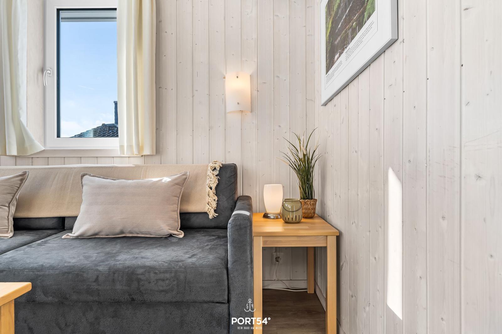 Graße Couch mit Kissen und Holztisch neben Fenster mit Blick auf Dach.