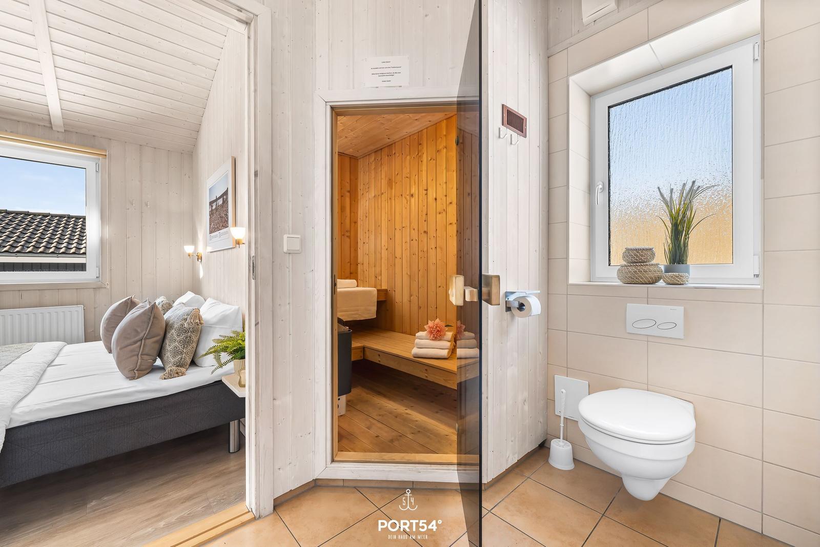Schlafzimmer mit Sauna und Badezimmer. Holzwände, Fenster und Toilette sichtbar.