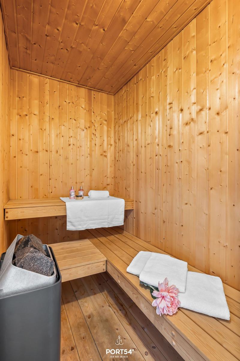 Sauna mit Holzwand, Bänken, Handtüchern und Blume