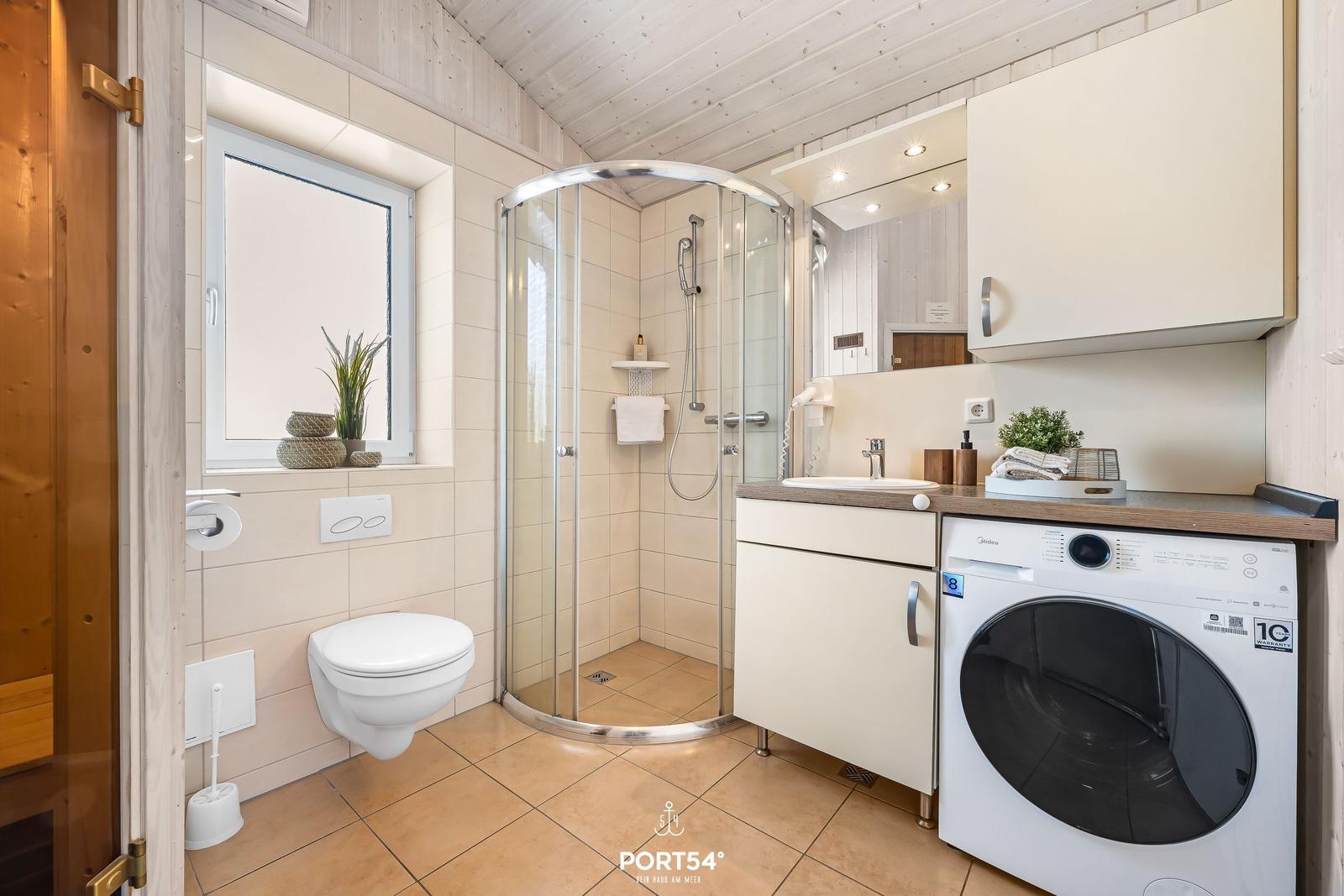 Badezimmer mit Dusche, Waschmaschine und Fenster.