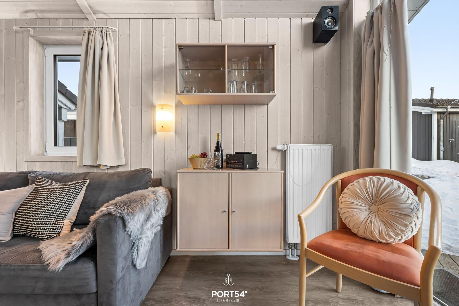 Ein Wohnzimmer mit Sofa, Stuhl, Bar und Fenster. Außenbereich mit Schnee.