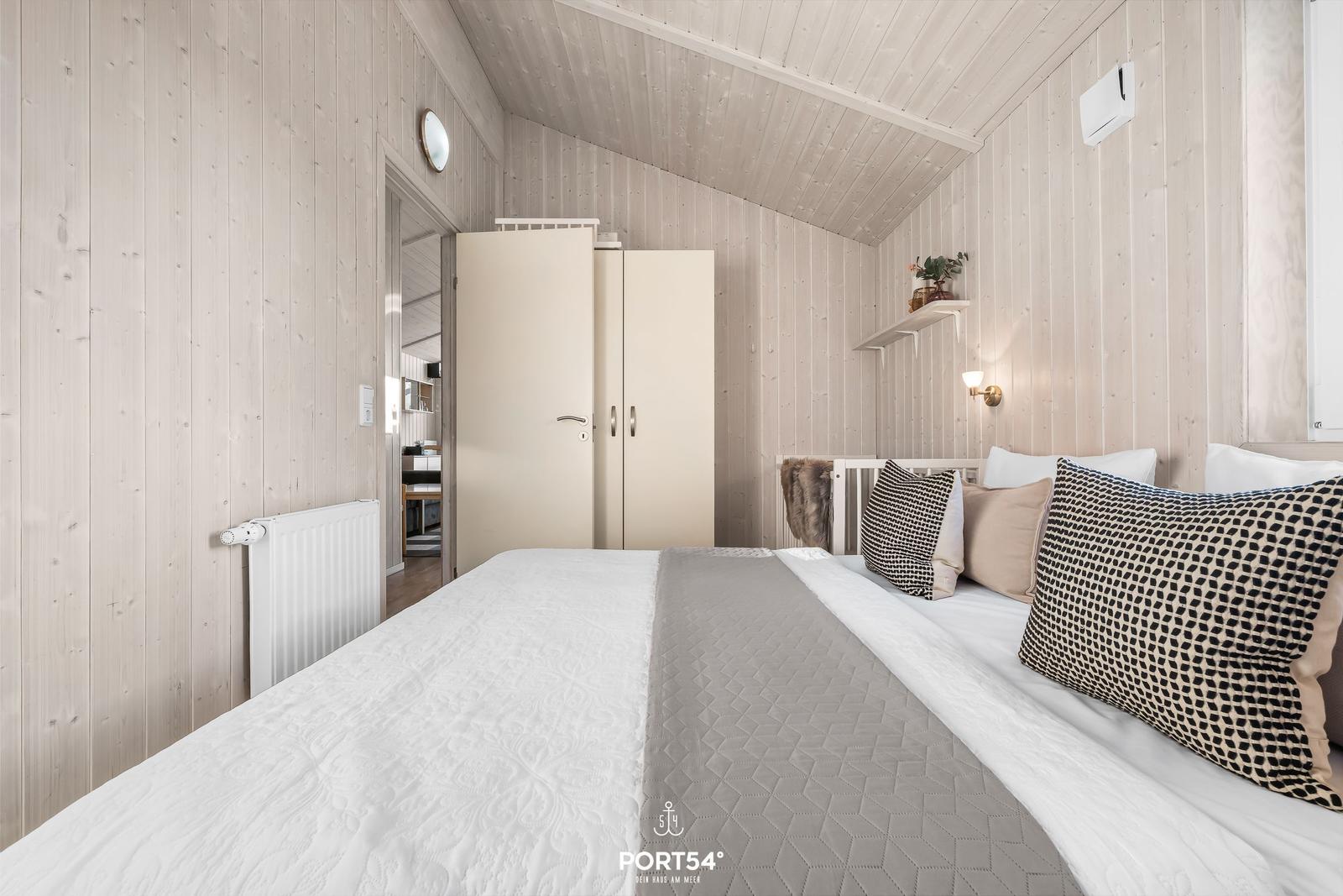Schlafzimmer mit Bett, Kleiderschrank und Holzwänden.