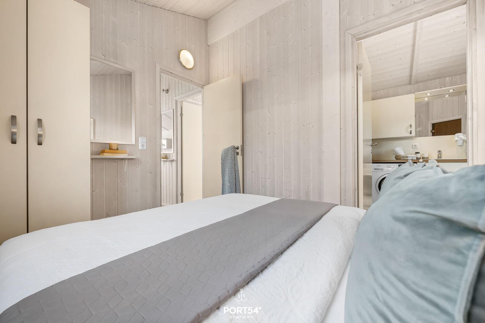 Schlafzimmer mit Bett, Kleiderschrank und Blick in die Küche.