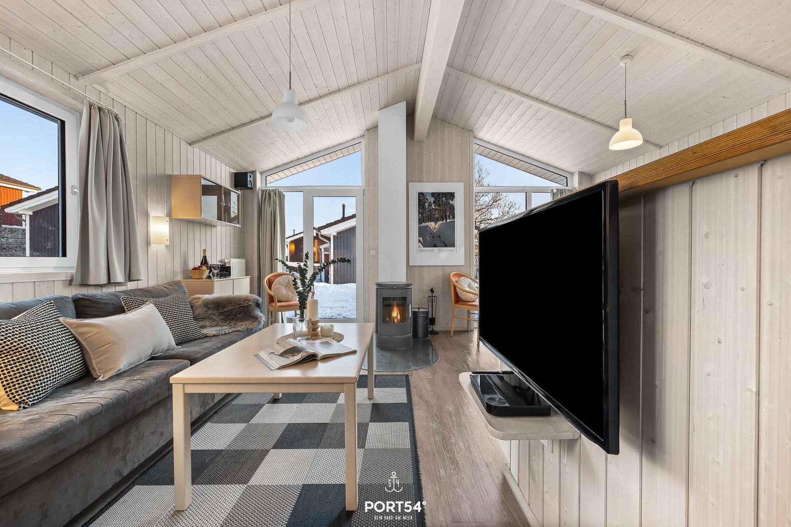 Wohnzimmer mit Sofa, Couchtisch, Kamin und Fernseher an Wand.