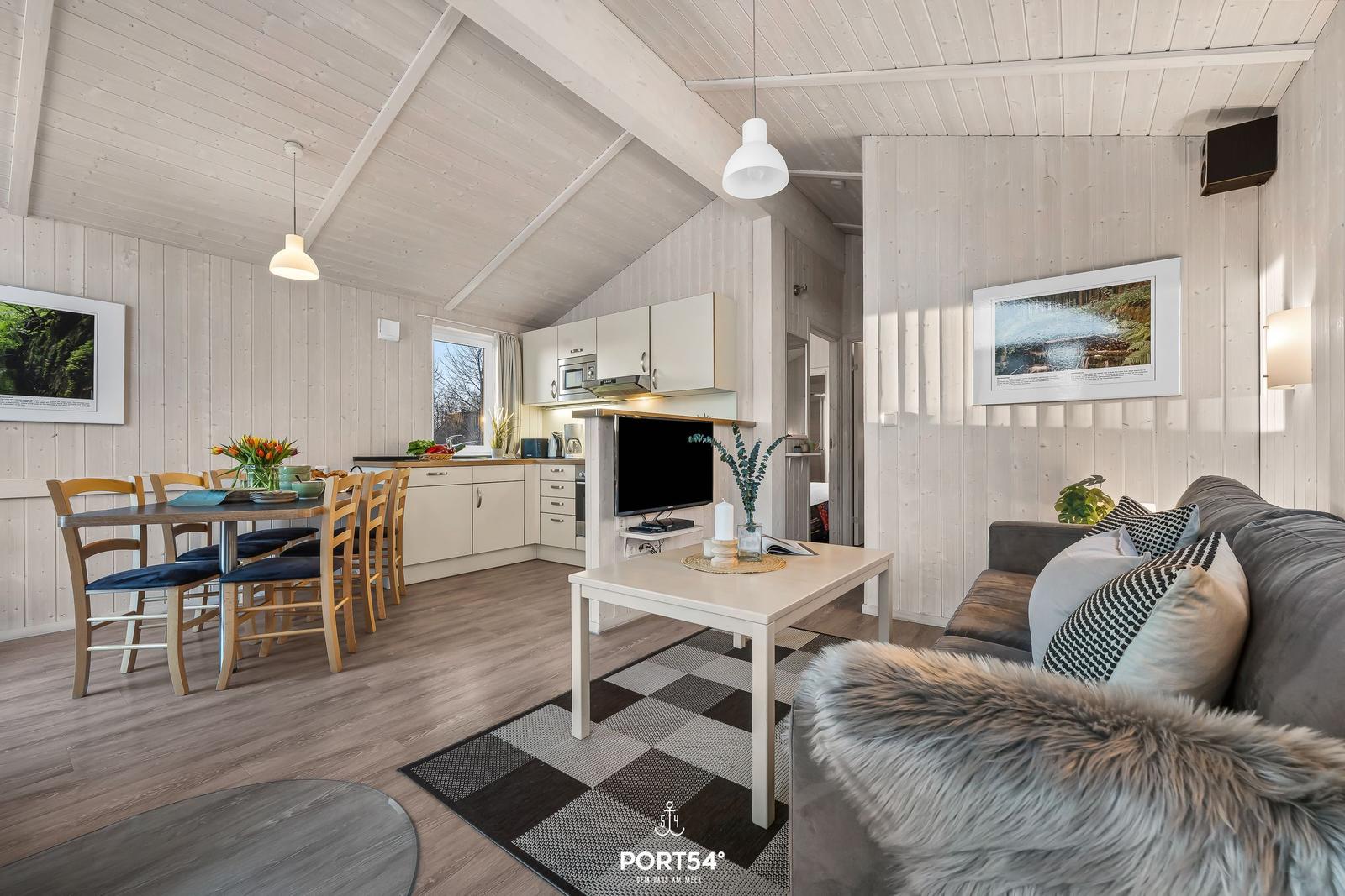 Wohn- und Essbereich mit Küche, Sofa und Essplatz. Holzwände und -boden.