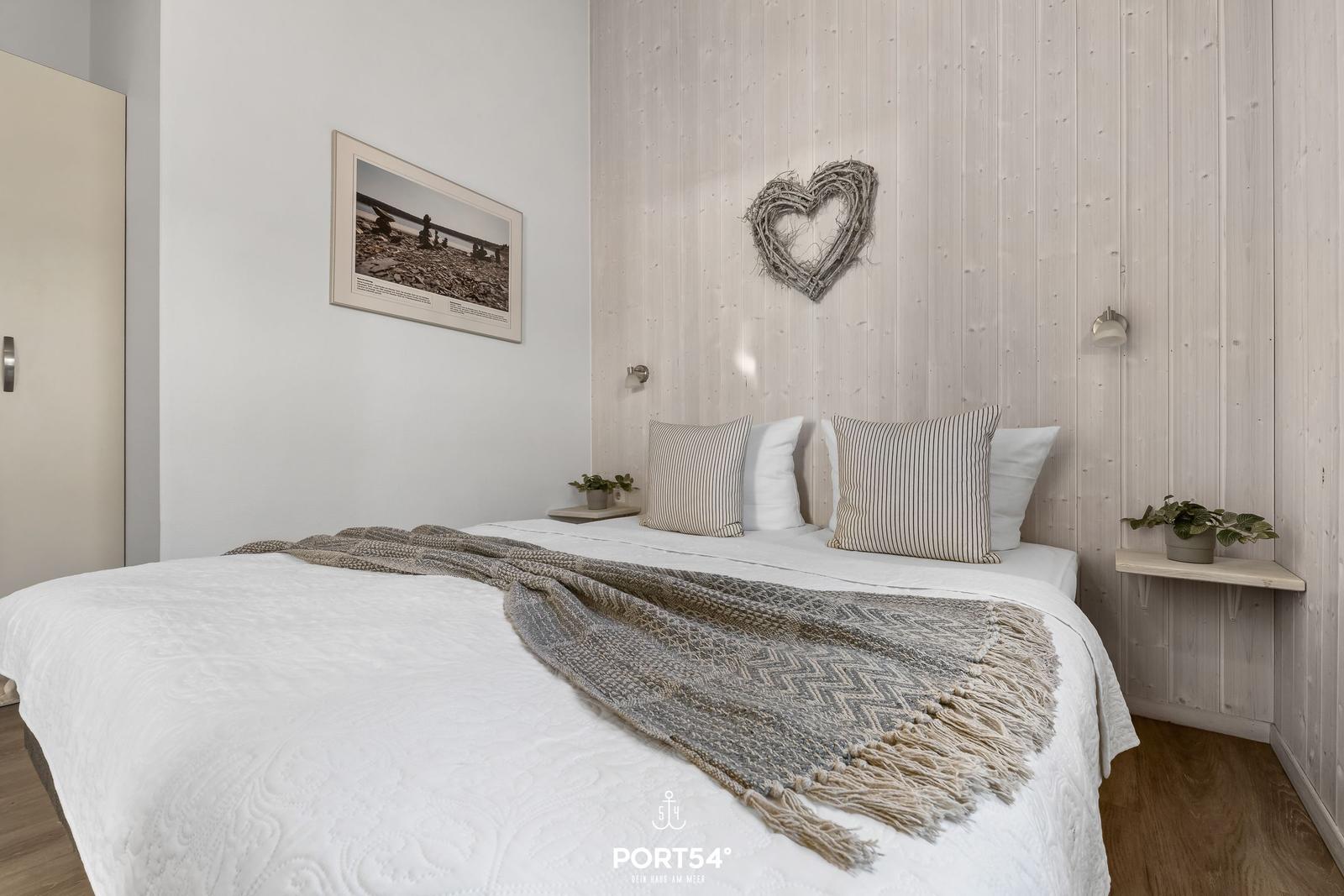 Schlafzimmer mit Bett, Holzwand und Bild an der Wand.