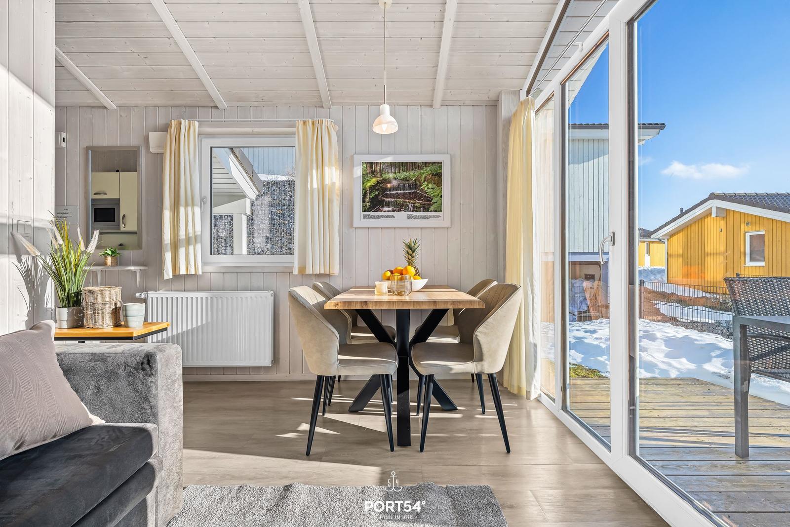 Essbereich mit Tisch und Stühlen, Glasfront zur Terrasse, Blick auf gelbes Haus.
