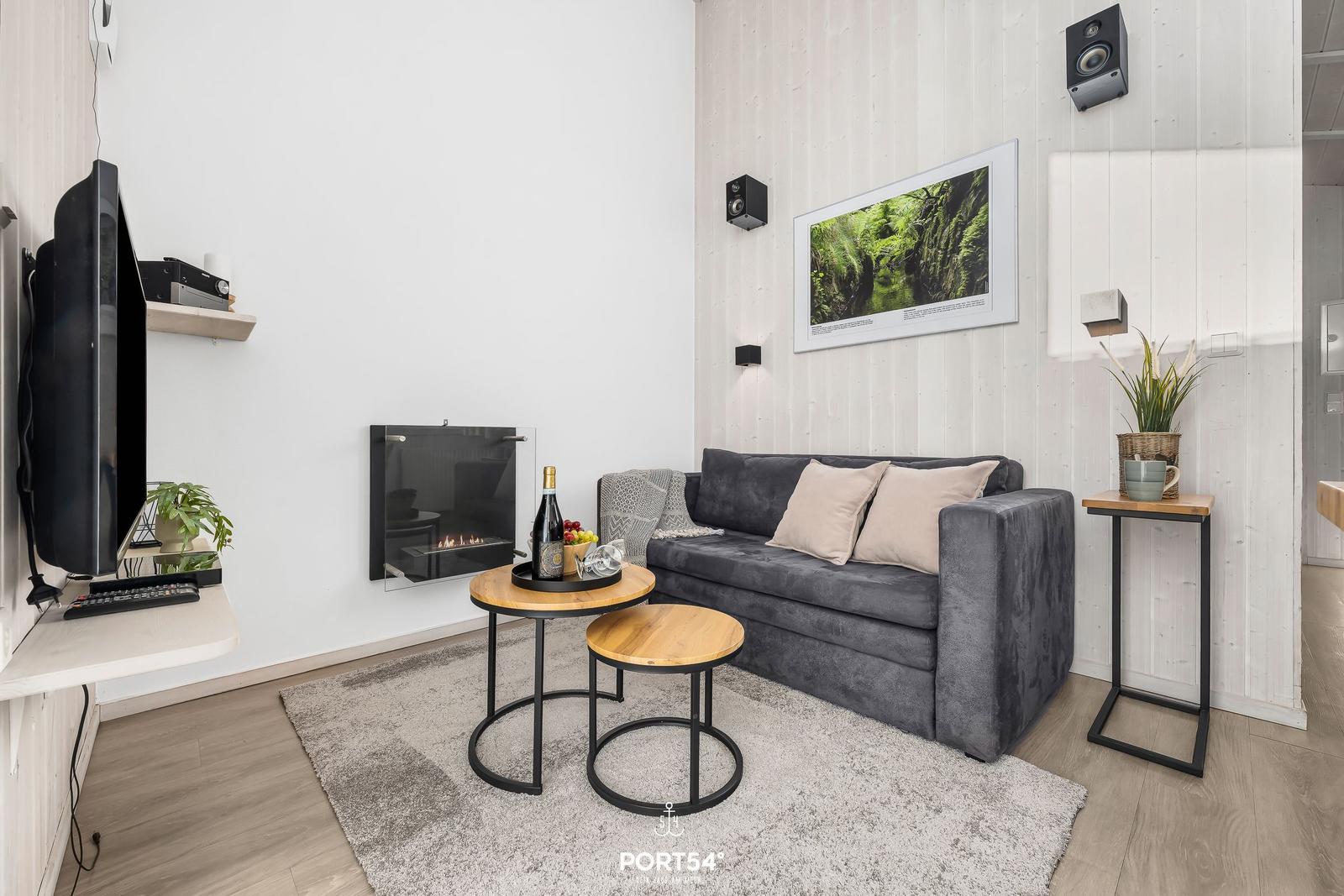 Wohnzimmer mit Sofa, Kamin und Fernseher. Holztische und Wandbild.