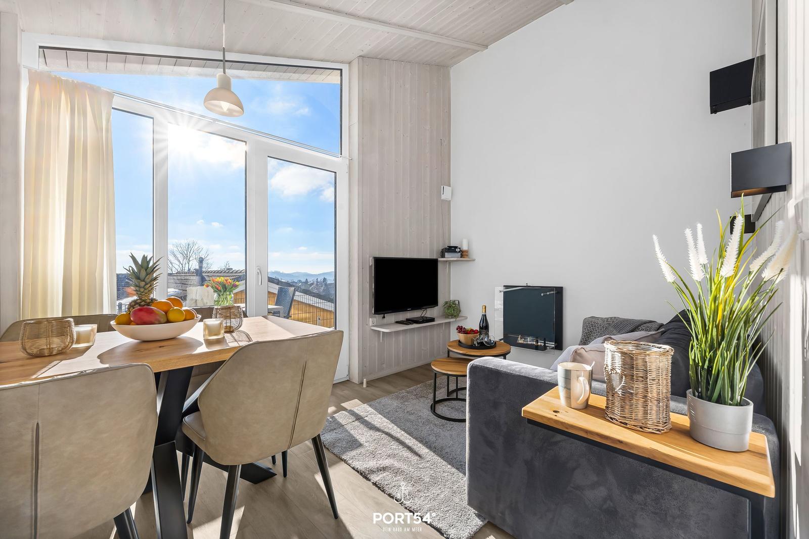 Wohn- und Essbereich mit großem Fenster, Sofa und Fernseher.