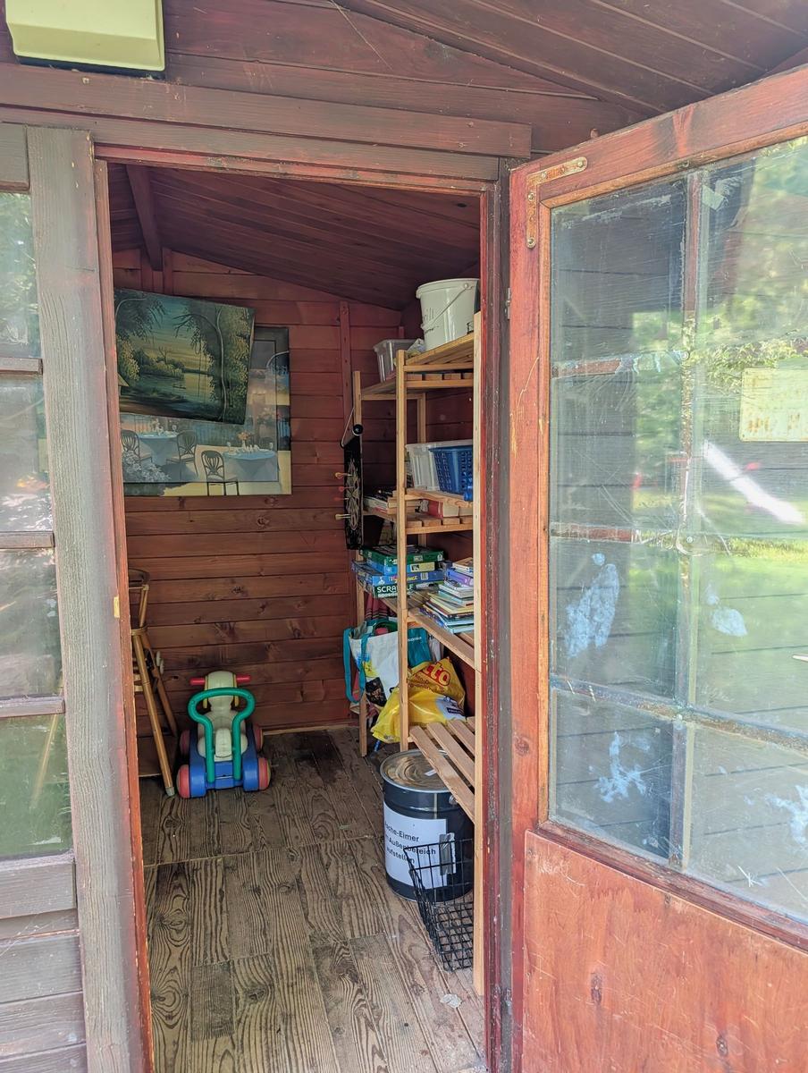 Eingangsbereich mit Holzwand, Regal, Kinderfahrzeug und Fenster.
