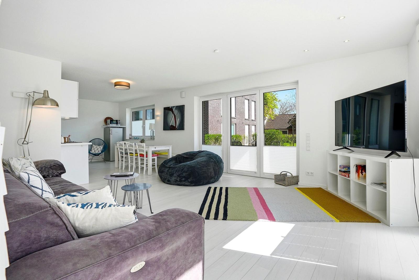 Living room with sofa, TV, and glass door to terrace