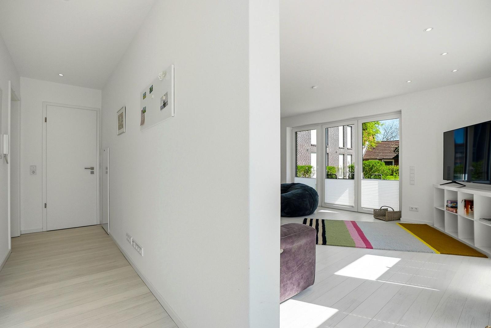 Hallway with living room. Living area with TV, seating, and garden view.