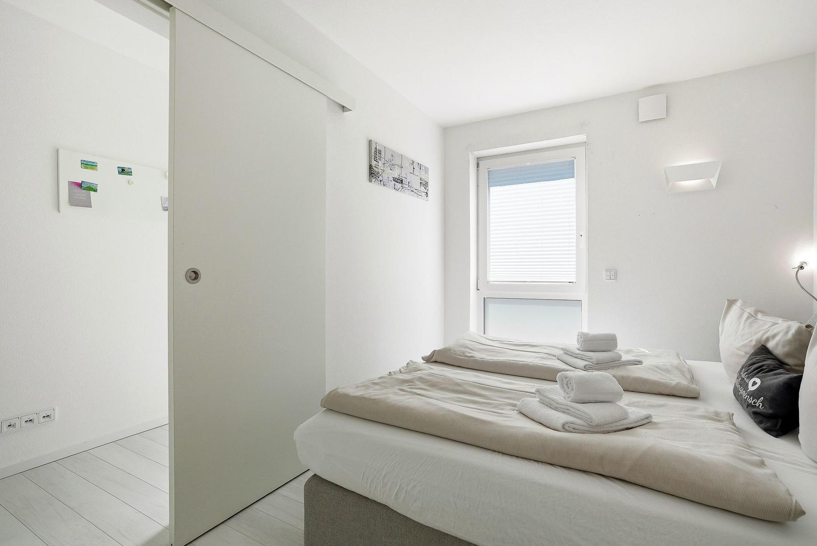 Bedroom with bed, window, and sliding door. Towel on bed.