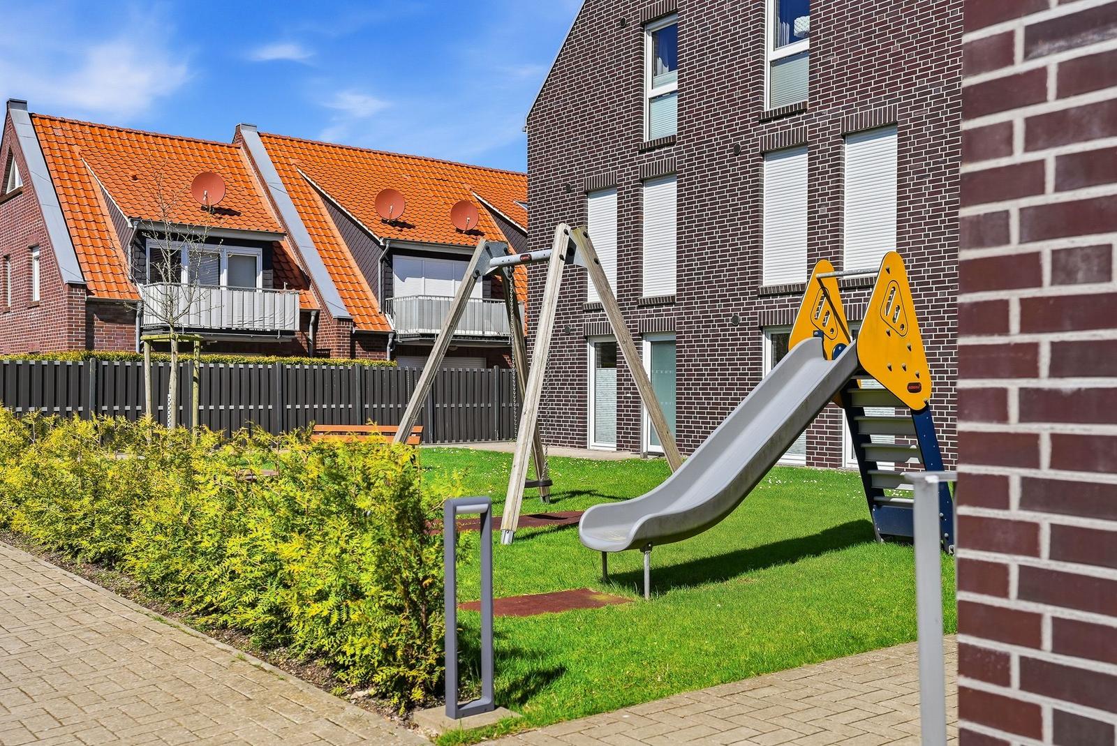Backyard with playground, slide, and swing in front of brick house.