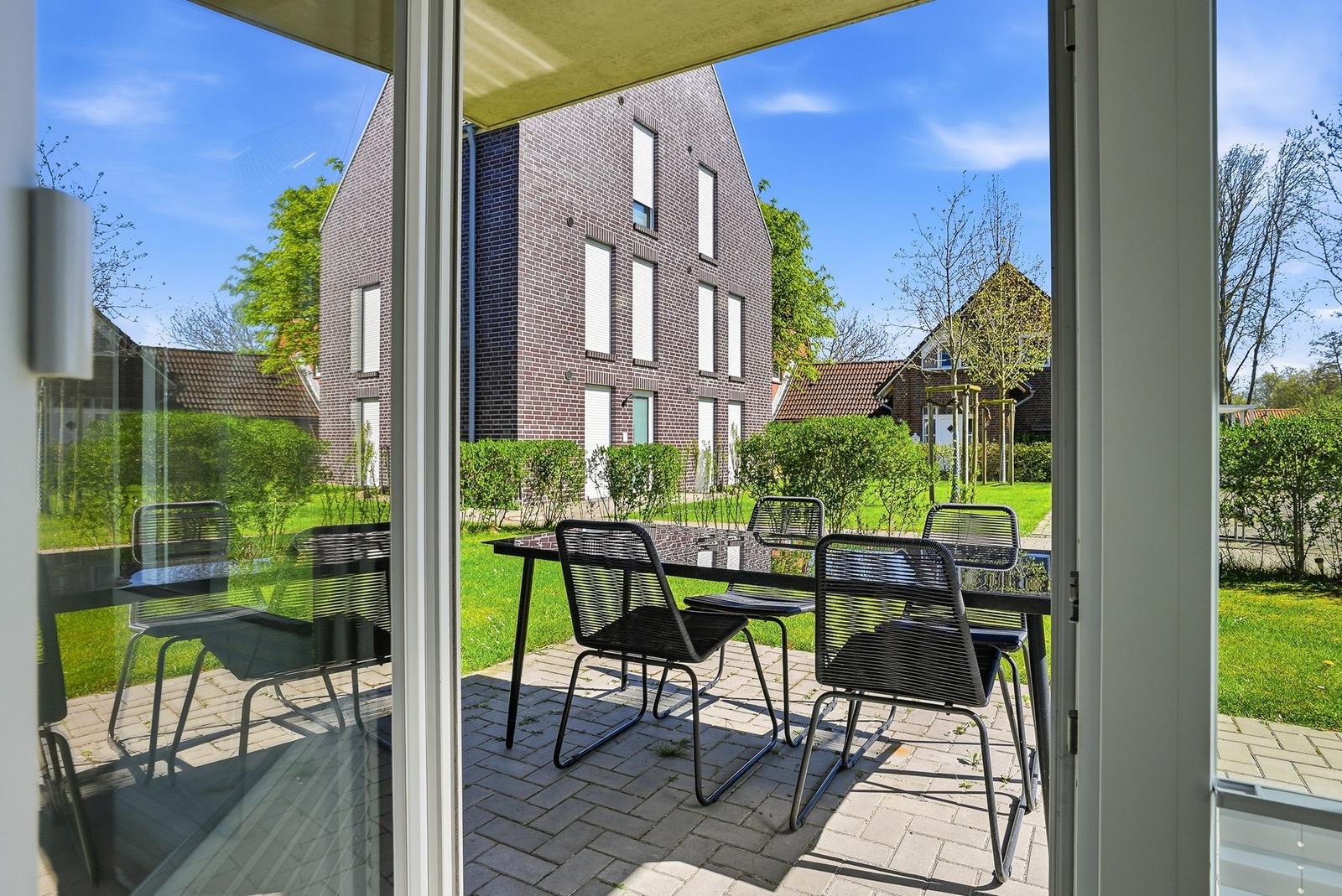 Terrace with table and chairs. View of garden and neighboring house.