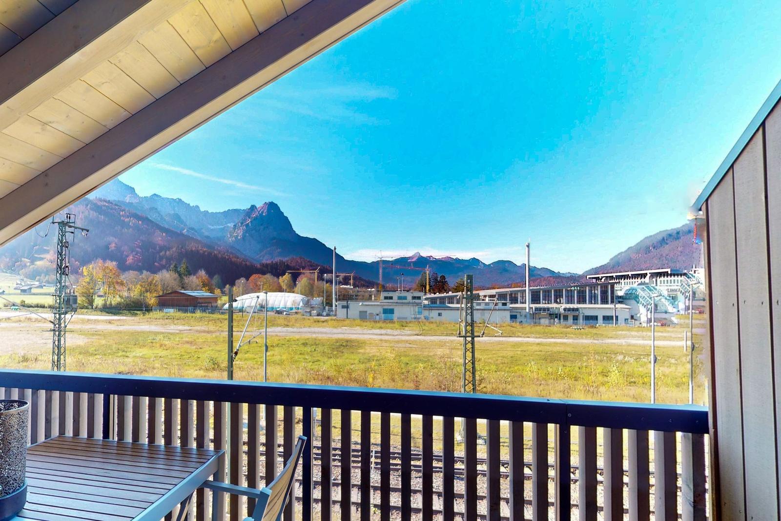 Balkon mit Blick auf Berge, Bahngleis und Gebäude.