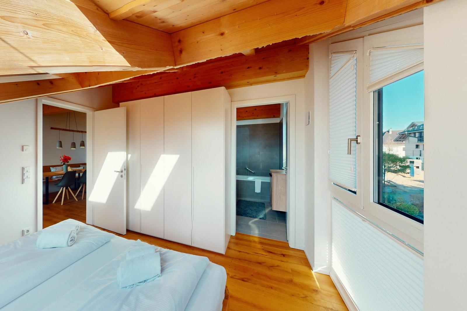 Schlafzimmer mit Blick auf Pool, weiße Schrankwand und Holzboden.