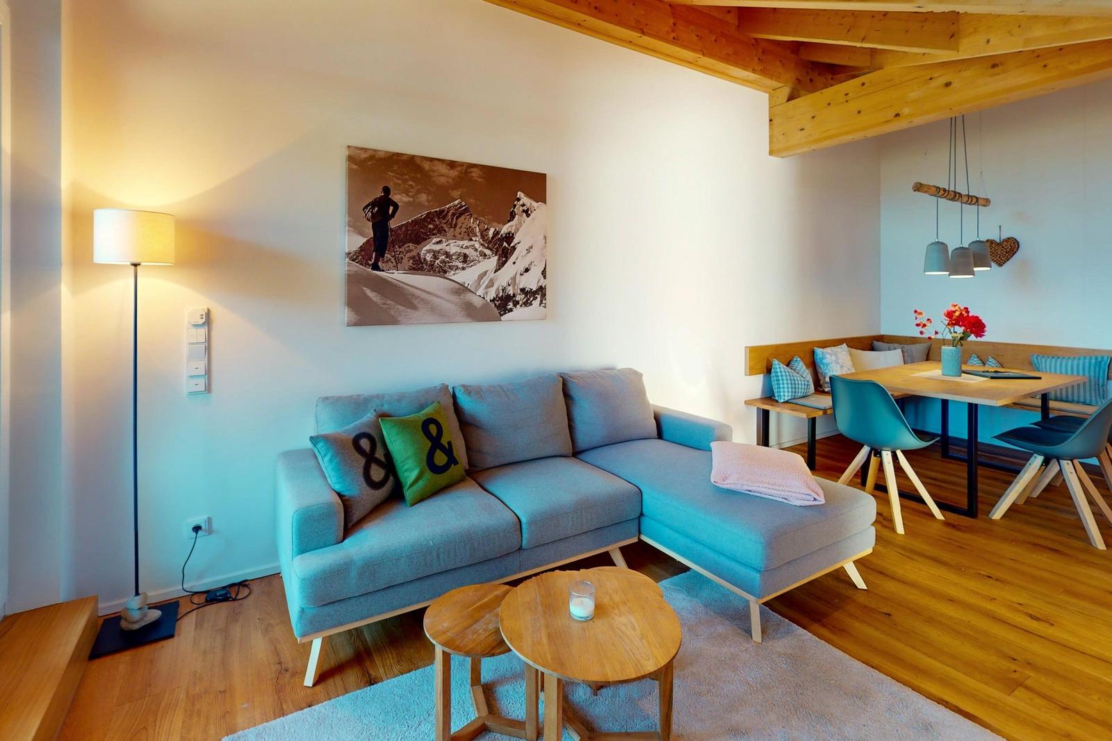 Wohn- und Essbereich mit Sofa, Tisch und Holzboden.