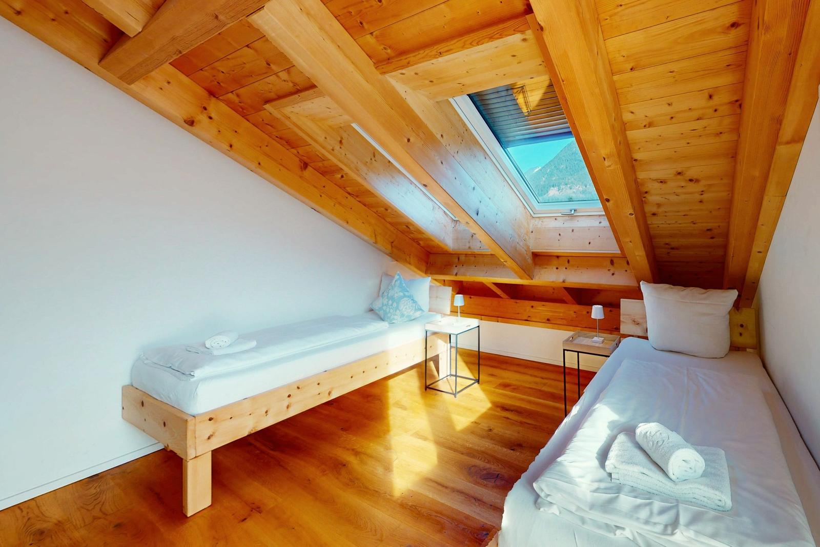 Zimmer mit zwei Betten, Holzboden und Dachfenster. Holzdecke und Nachttische.