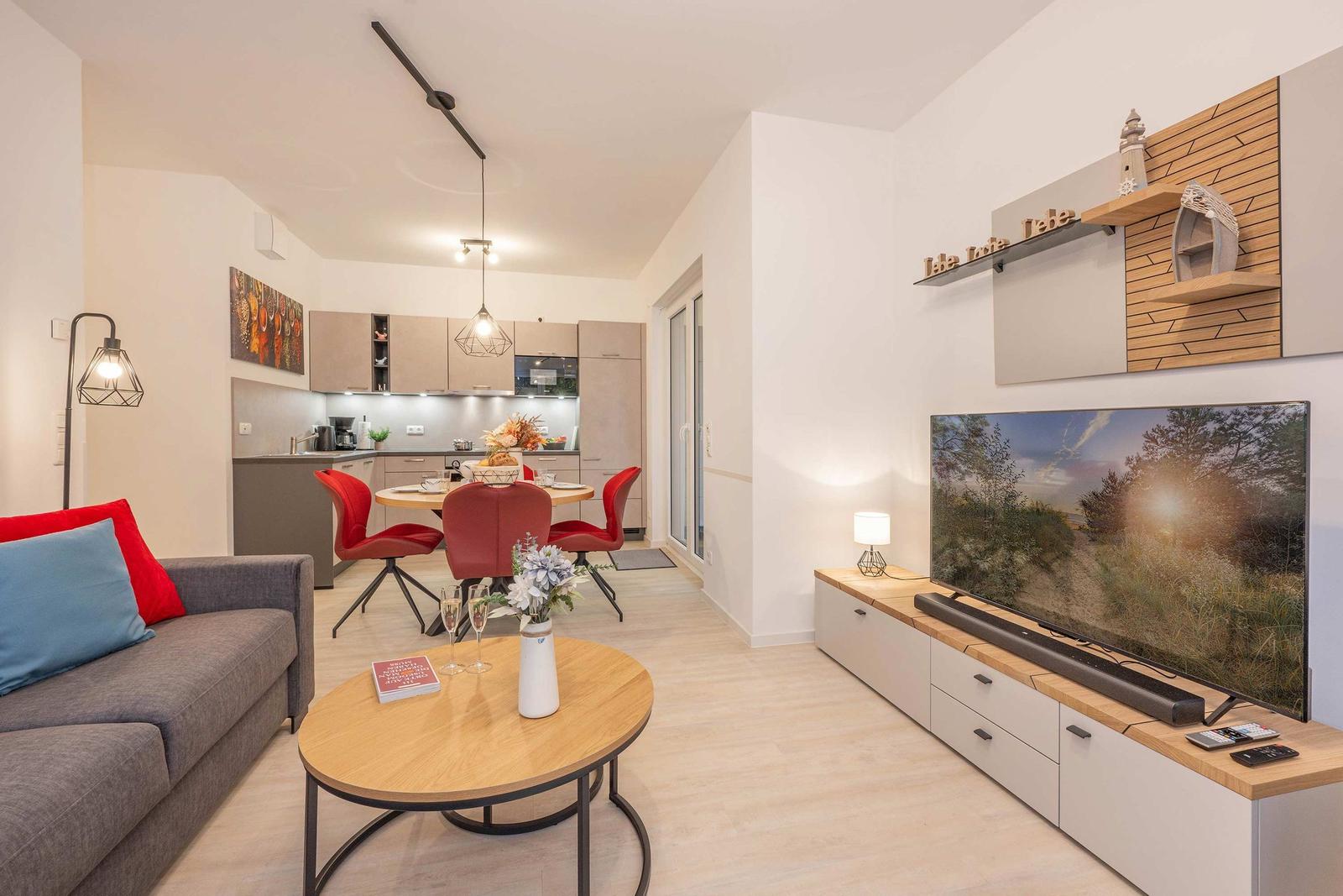 Wohnbereich mit Sofa, Esstisch, Küche und Fernseher.