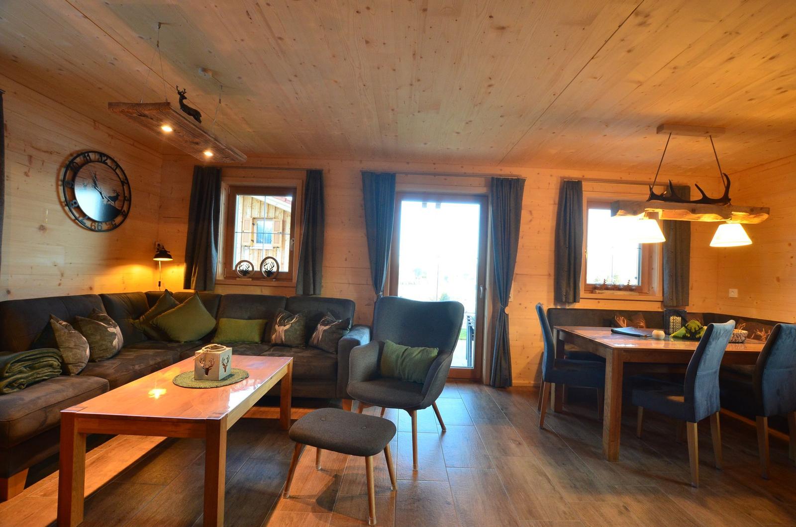 Wohn- und Essbereich mit Holzdecke, Sofa, Stuhl und Tisch.